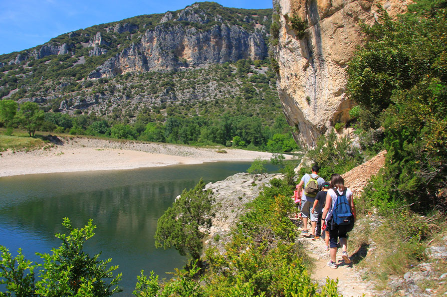 Famille en randonnée sur un sentier au bord de la rivière dans les Gorges de l’Ardèche