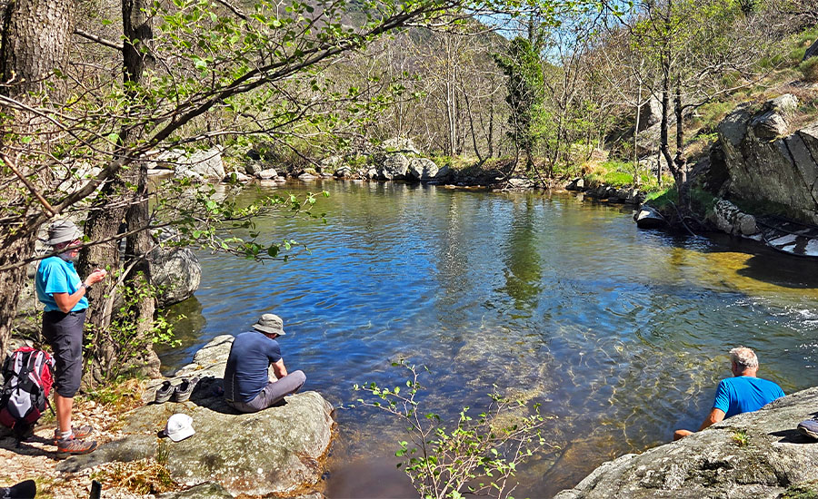 Randonneurs en pause au bord d’une rivière claire au cœur de la nature ardéchoise lors d’un séjour Cap Ardèche